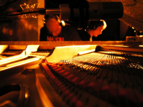 Nello sfondo di un pianoforte, alcuni musicisti preparano gli strumenti per una jam session